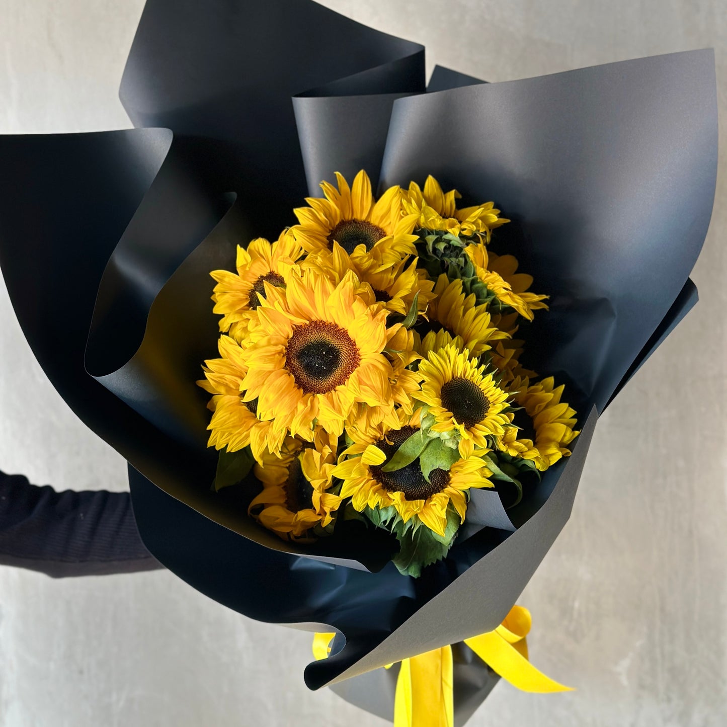 A person holding a stunning bouquet called the Sungold Surprise from Flowers on Norton St, presenting it for a special celebration.