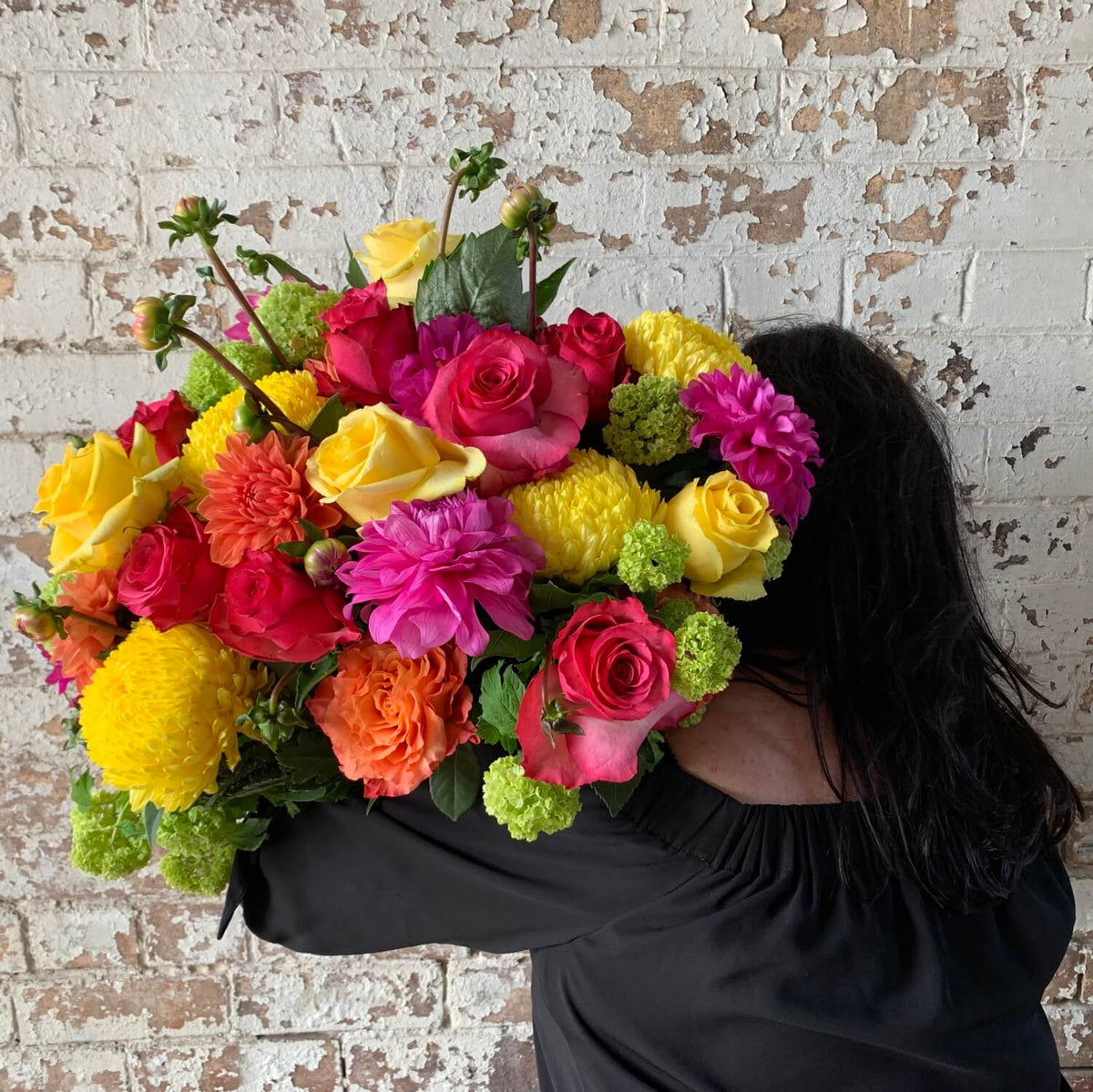 A woman holding a bouquet of vibrant "Summer Harvest by Penny" from Flowers on Norton St.