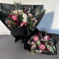 Displayed against a light gray background, two elegant bouquets from Flowers on Norton St's Little Native Bunch 2024 feature pink and white protea flowers accented with eucalyptus leaves and delicate greenery, all wrapped in black paper.